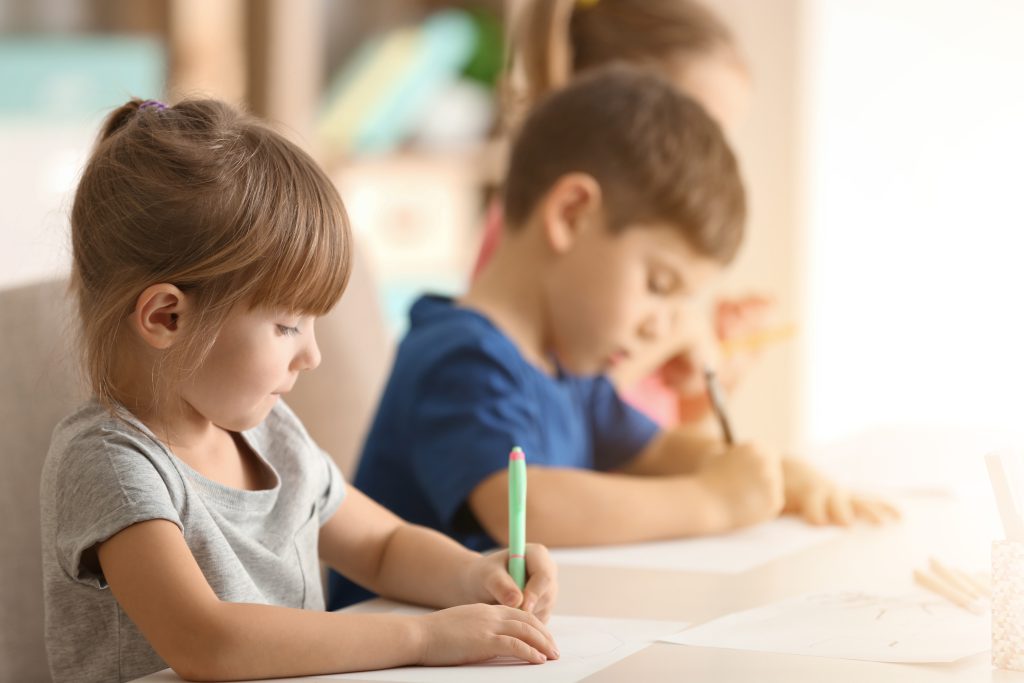 Deux enfants apprennent à écrire sur leur cahier.